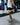 A man stretches his quad muscles in a white tee and black shorts.